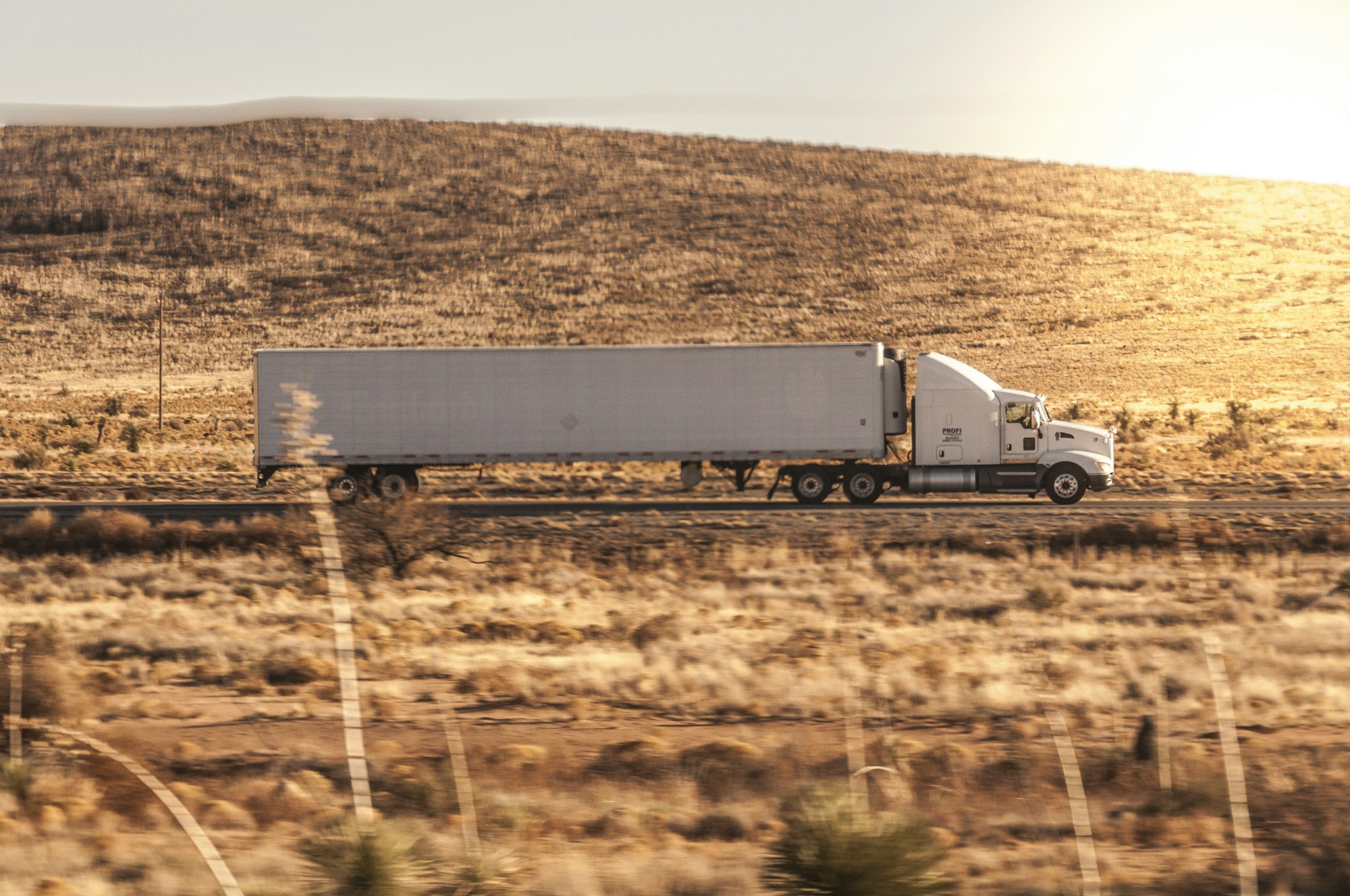 White semi-truck traveling on an open rural highway